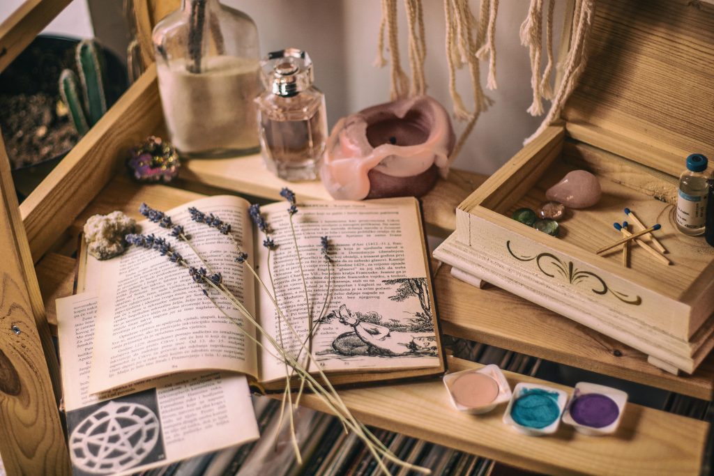 Aesthetic setup with books, lavender, crystals, and candles on a wooden shelf.